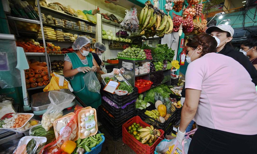 No Peru, mulheres fazem compras em quitanda de máscara Foto: CRIS BOURONCLE / AFP