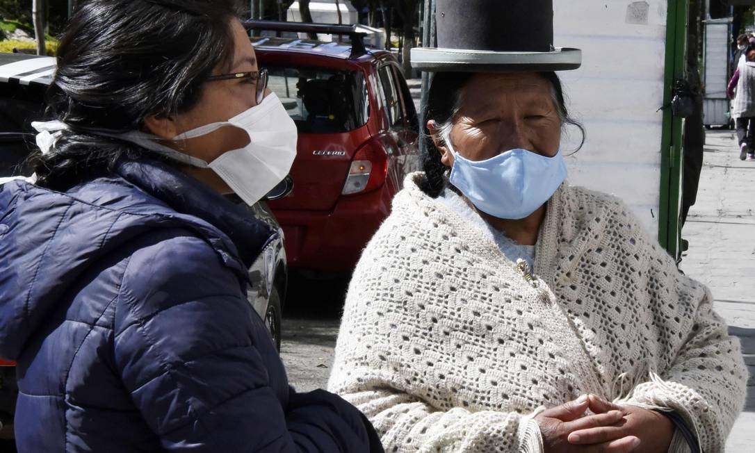 Mulheres usam máscaras em mercado de rua em La Paz, durante isolamento total ordenado pelo governo Foto: AIZAR RALDES / AFP