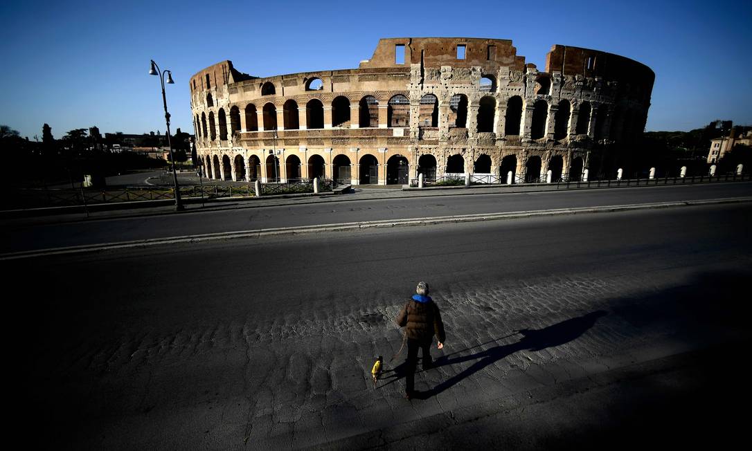 Homem caminha com cachorro em frente ao Coliseu, em Roma, na Itália Foto: FILIPPO MONTEFORTE / AFP