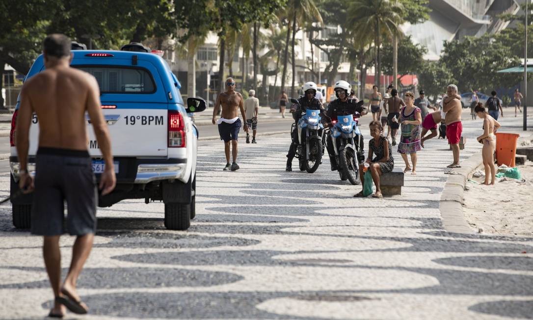 Policiais e Guarda Municipal atuam na Orla de Copacabana tentando conter pessoas na calçada e retirando banhistas da areia no fim de semana Foto: Ana Branco / Agência O Globo