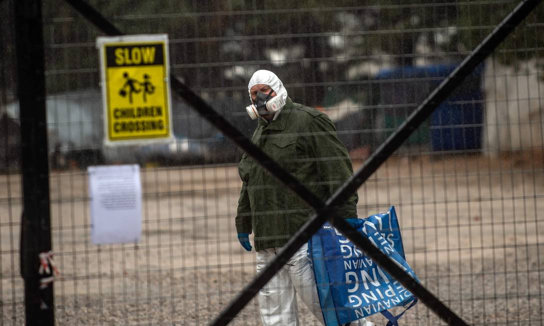 Homem usa uma máscara de proteção enquanto anda no camp0 de Malakasa, espaço destinado a refugiados. Foto: ANGELOS TZORTZINIS / AFP