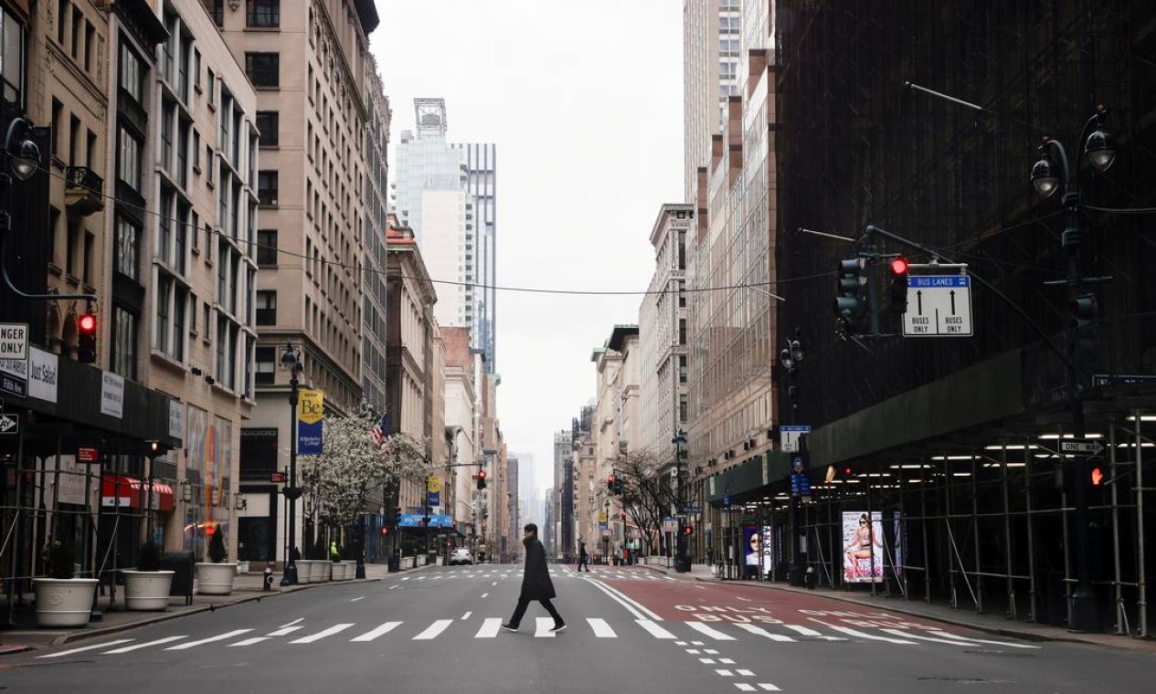 Homem atravessa a 5ª Avenida quase vazia no centro de Manhattan durante o surto de coronavírus na cidade de Nova York, EUA Foto: MIKE SEGAR / Reuters