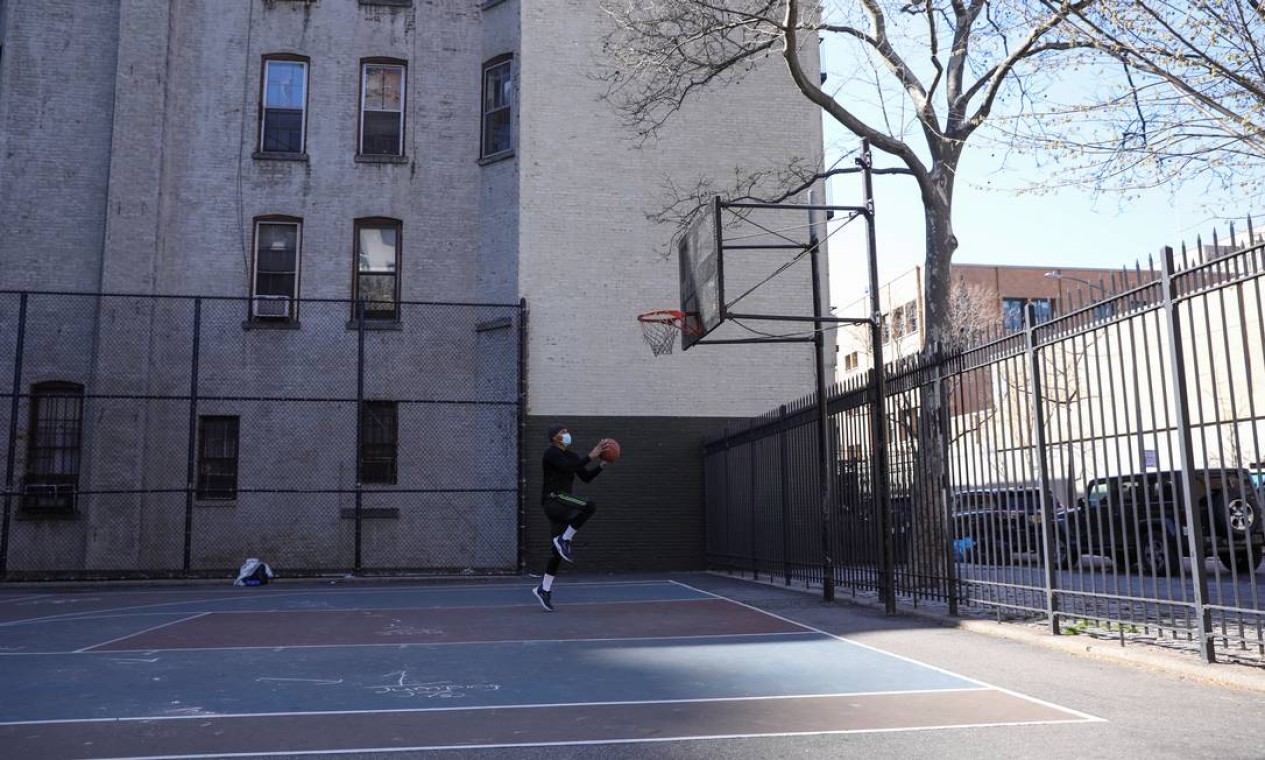 Um jovem joga basquete sozinho e usa uma máscara protetora em Manhattan, Nova York Foto: CAITLIN OCHS / REUTERS
