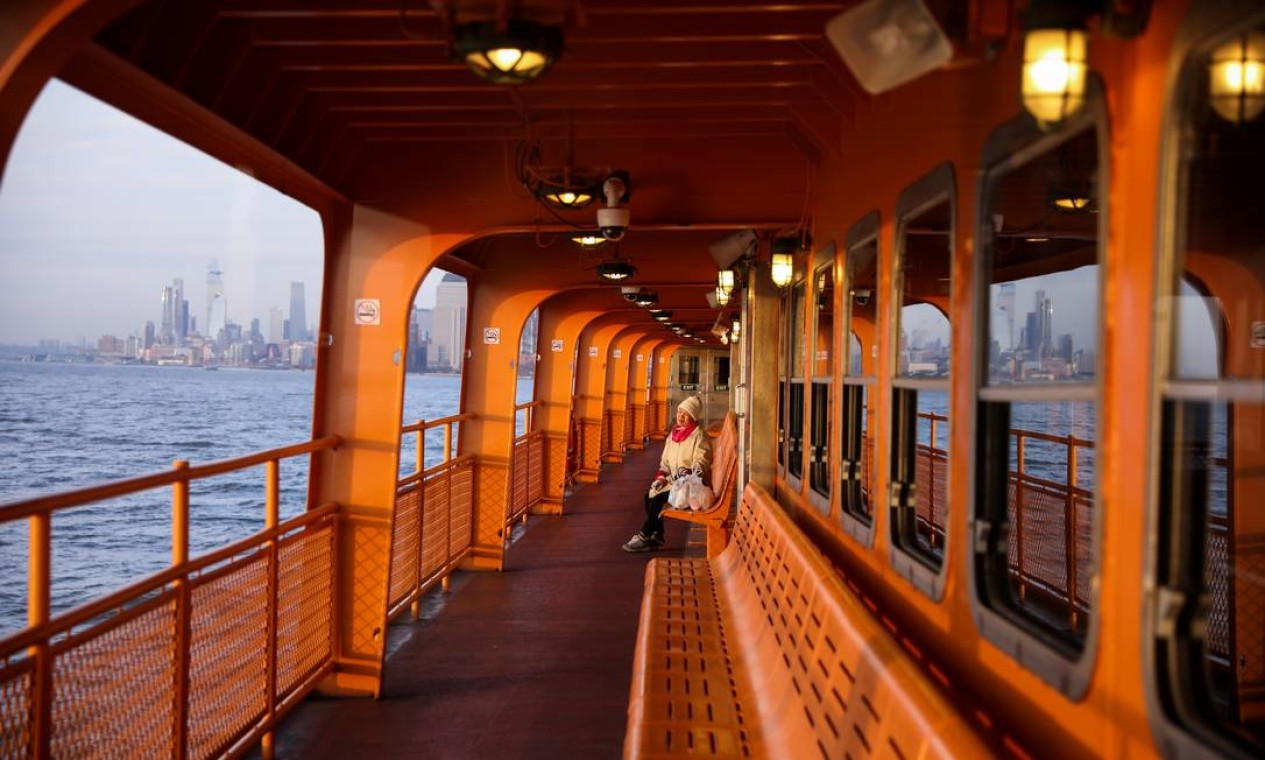 Uma passageira aprecia o por do sol sozinha no convés superior de um ferry de Staten Island durante o surto de Covid-19 em Manhattan, Nova York Foto: CAITLIN OCHS / REUTERS