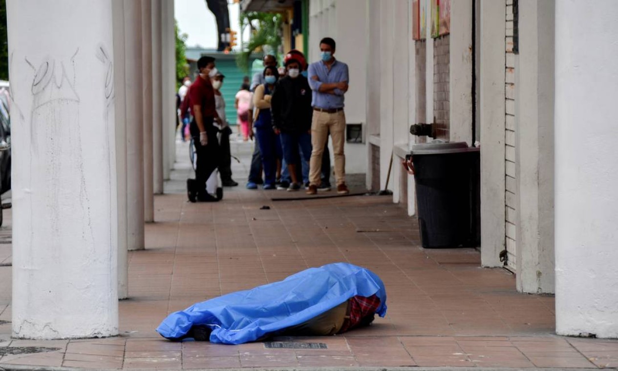 Pessoas fazem fila do lado de fora de uma loja perto do corpo estirado na calçada Foto: STRINGER / REUTERS