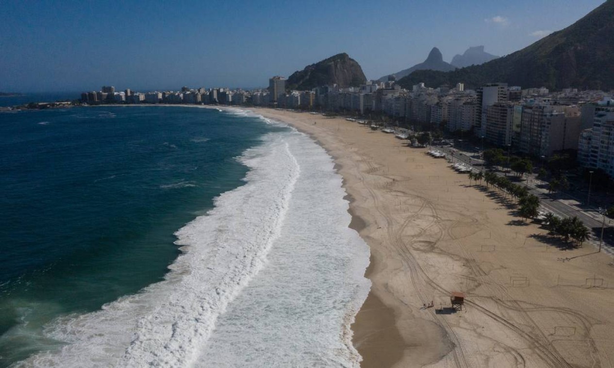 Vista do alto, a Praia de Copacabana parece completamente vazia, embora pequenos grupos de pessoas ainda insistam em ocupar a faixa de areia, o que está proibido por decreto Foto: Brenno Carvalho / Agência O Globo