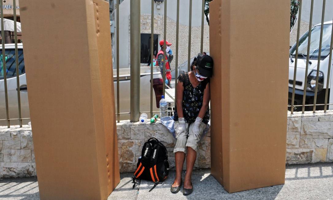 Mulher de máscara e luvas vela a caixa usada como caixão em Guayaquil, Equador Foto: JOSE SANCHEZ / AFP