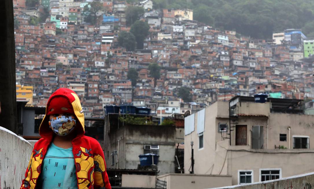 Moradora se protege com máscara diante da favela da Rocinha Foto: FABIO MOTTA / Agência O Globo