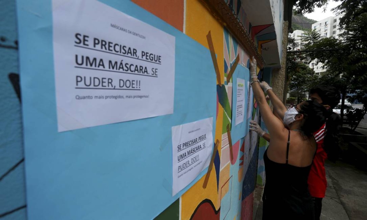 "Se precisar, pegue uma máscara, se puder, doe", diz cartaz colado no muro da destinado a doações Foto: FABIANO ROCHA / Agência O Globo