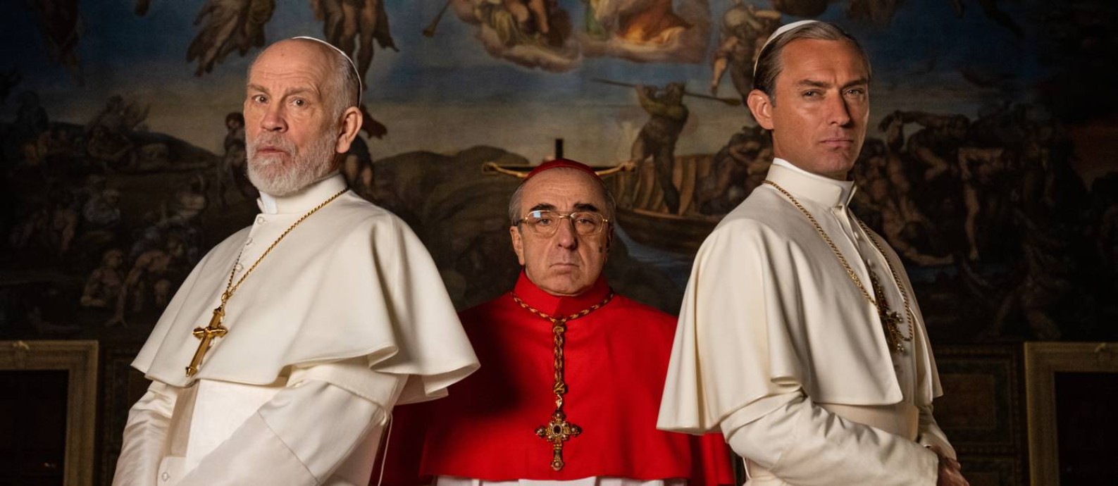 Dois papas e um cardeal. Jude Law, John Malkovich e Silvio Orlando posam no set de 'The new pope', que chega ao Brasil pela FOX Foto: Gianni Fiorito