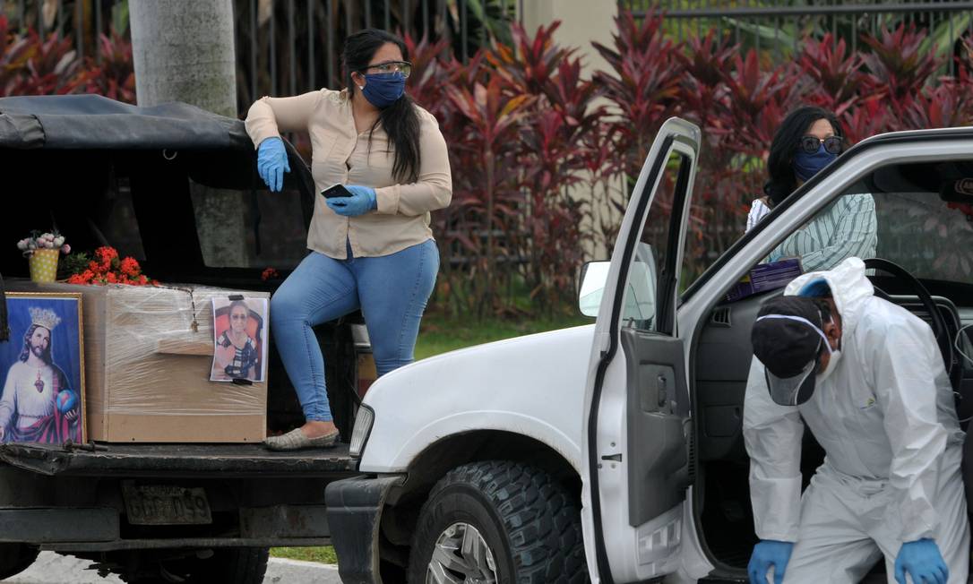 Parentes de um vítima do novo coronavírus chegam com um caixão de papelão ao cemitério Paque de la Paz, em Guayaquil, no Equador Foto: JOSE SANCHEZ / AFP