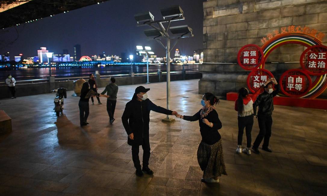 Casais dançam em um parque em Wuhan, cidade que registrou os primeiros casos da Covid-19 Foto: HECTOR RETAMAL / AFP