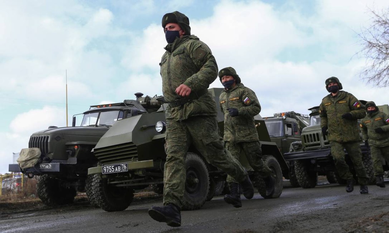 Militares russos usando máscaras de proteção passam por veículos militares durante o ensaio Foto: ALEXEI KOLCHIN / REUTERS