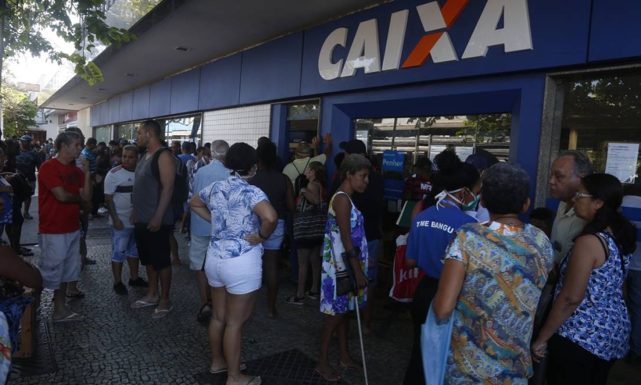 Beneficiários se agomeram me frente à agência da Caixa Econômica Federal, no calçadão de Bangu, Foto: Fabiano Rocha / Agência O Globo