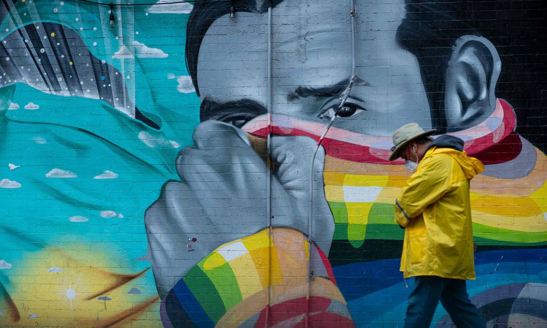 Homem passa em frente a mural em Nova York, cidade mais atingida pelo coronavírus nos EUA Foto: JOHANNES EISELE / AFP