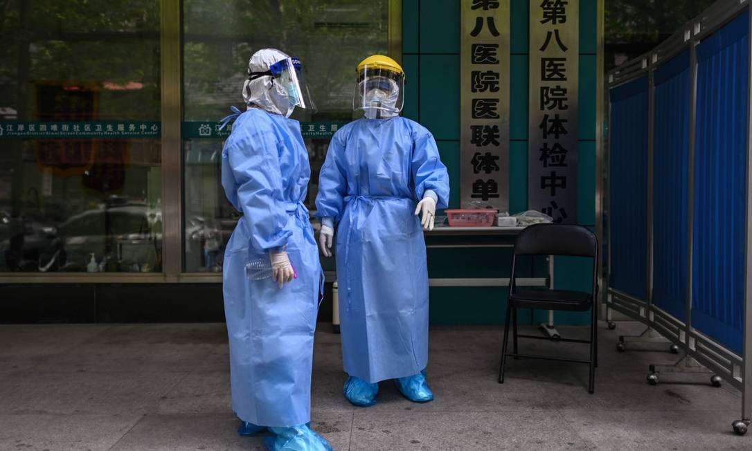 Médicos com equipamento de proteção em centro de testagem para a Covid-19 em Wuhan Foto: HECTOR RETAMAL / AFP
