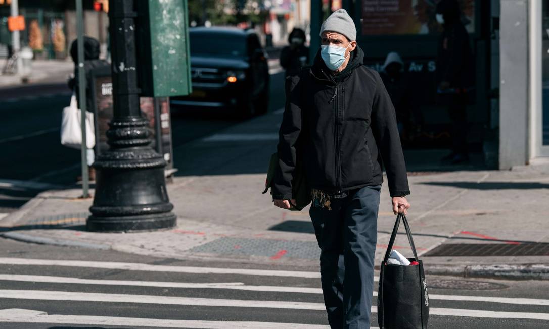 De máscara, pedestre atravessa a rua em Nova York Foto: Scott Heins / AFP / 17-04-2020