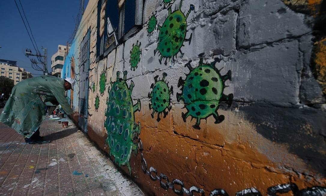 Em Gaza, um artista pinta um muro em apoio aos palestinos detidos em penitenciárias israelenses em meio à pandemia do novo coronavírus Foto: Mohammed Abed / AFP