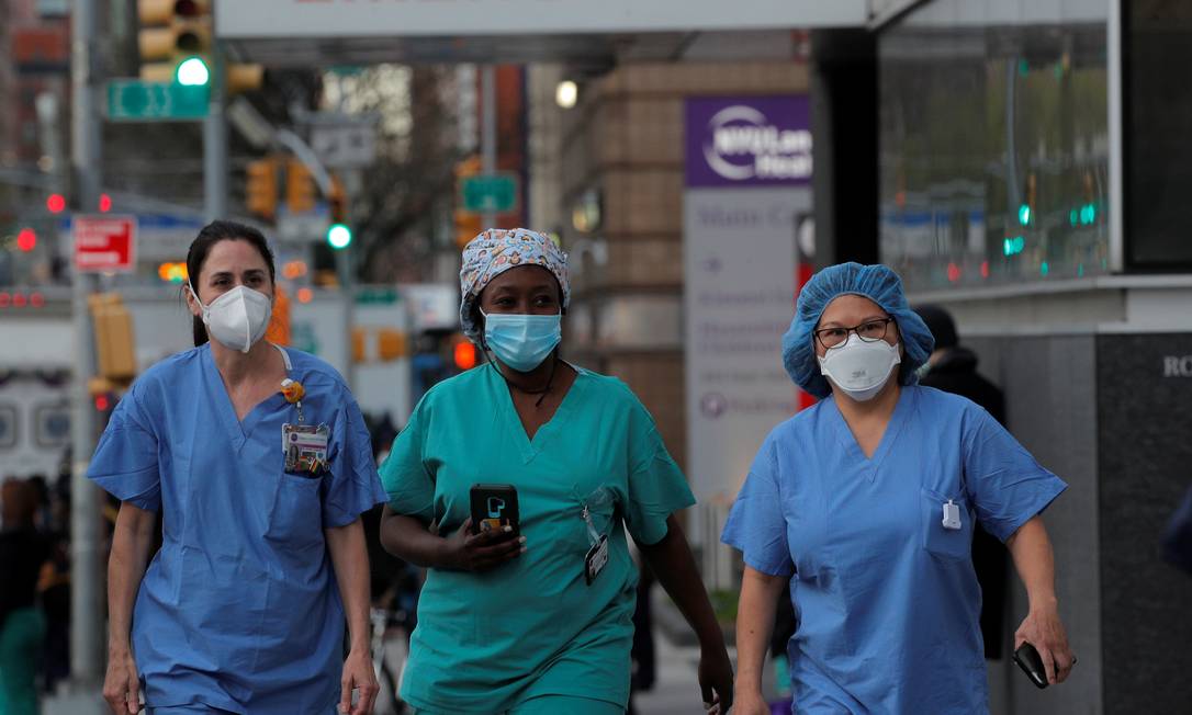Profissionais de saúde andam por Manhattan, em Nova York Foto: BRENDAN MCDERMID / REUTERS