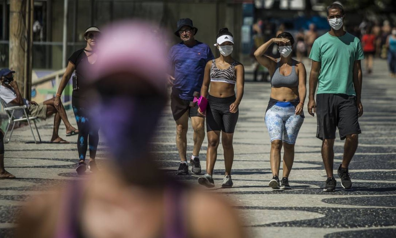 Pessoas usando máscaras caminham no calçadão de Copacabana no feriado de São Jorge Foto: Guito Moreto / Agência O Globo