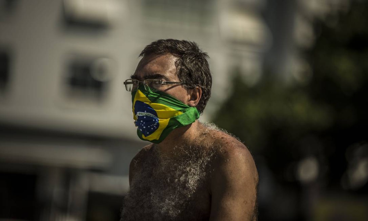 Homem usa uma bandana como proteção enquanto caminha na orla de Copacabana Foto: Guito Moreto / Agência O Globo
