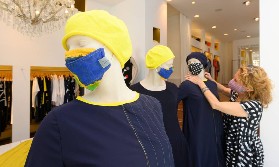 Funcionária decora manequins com máscaras em loja reabeerta na Alemanha Foto: THOMAS KIENZLE / AFP