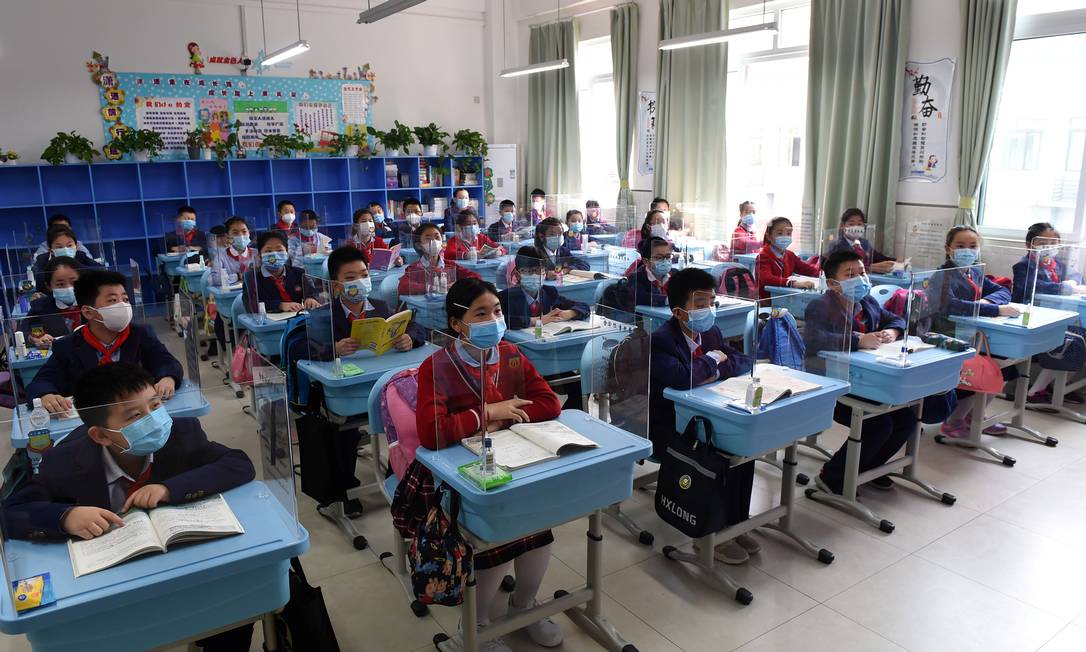 Estudantes usando máscaras sentam-se em uma sala de aula com divisórias em suas mesas em uma escola em Chongqing, na China Foto: STRINGER / REUTERS/27-04-2020