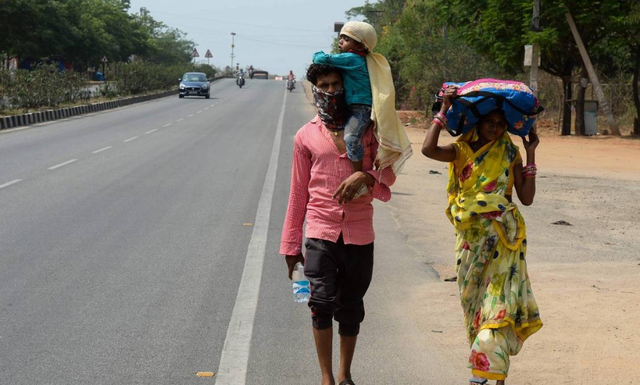 Família de trabalhadores do estado indiano de Maharashtra caminha pela rodovia nacional 44, nos arredores de Hyderabad, para chegar a suas cidades natal durante o bloqueio nacional imposto pelo governo como uma medida preventiva contra o coronavírus Foto: NOAH SEELAM / AFP
