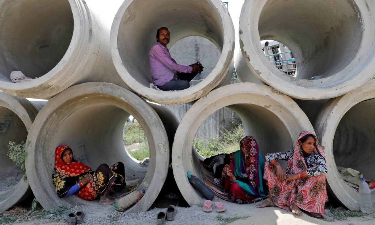 Trabalhadores migrantes descansam em manilhas à beira da estrada Foto: PAWAN KUMAR / REUTERS