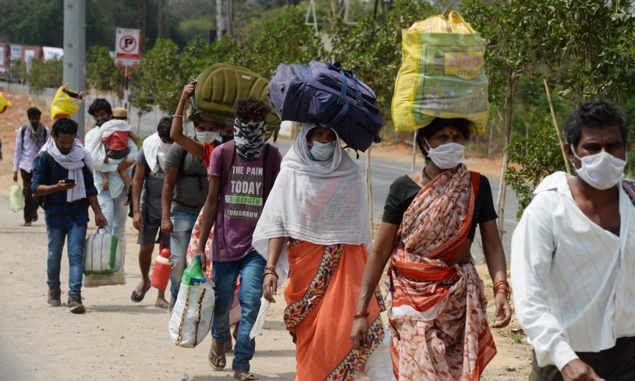 Trabalhadores migrantes do estado indiano de Maharashtra andam ao longo de uma rodovia nacional 44, que norte e sul da Índia e é considerada uma das maiores rodovias do mundo, para chegar às suas cidades natal Foto: NOAH SEELAM / AFP