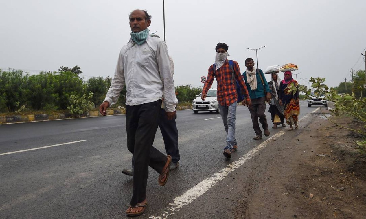 Trabalhadores migrantes e seus familiares caminham em grupo, carregando pertences em uma estrada de Faridabad, em direção a Uttar Pradesh Foto: MONEY SHARMA / AFP