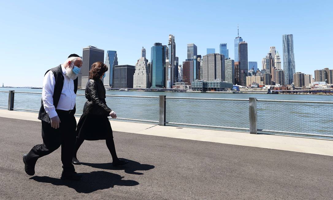 Casal caminha no Brooklyn, em Nova York, usando máscaras: um dos maiores centros financeiros do mundo está paralisado há semanas Foto: AL BELLO / AFP