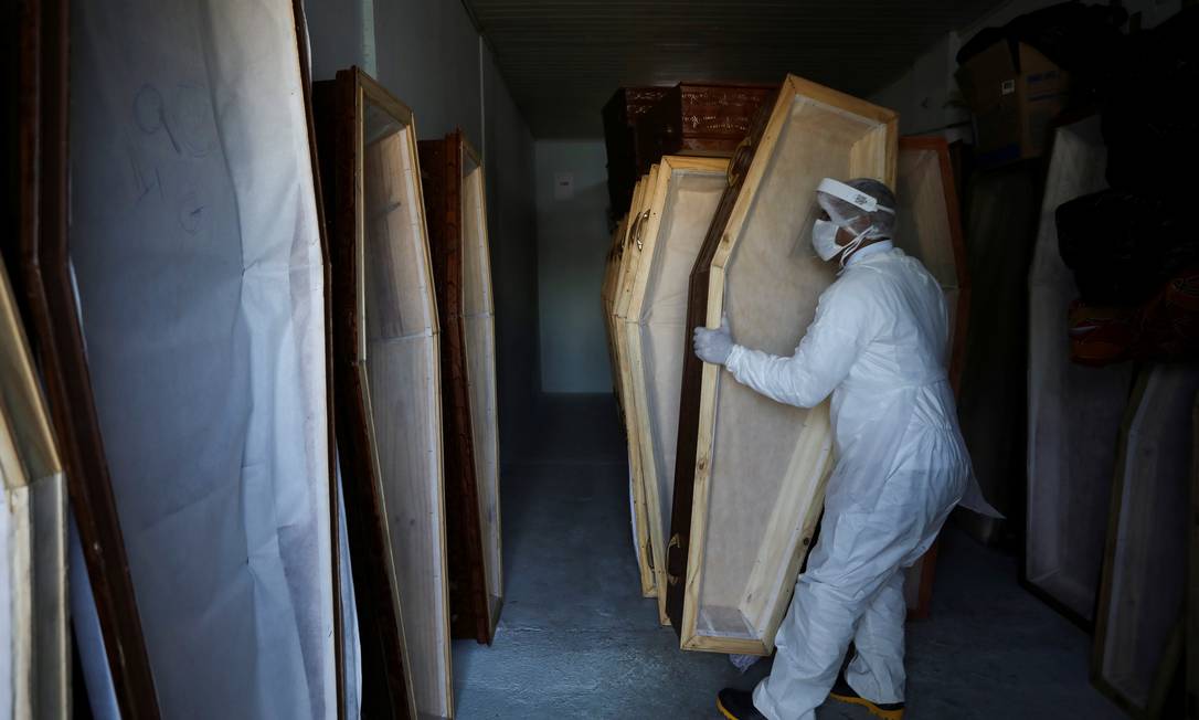 Funcionário com roupa protetora prepara caixões para mortos por Covid-19 em Manaus Foto: BRUNO KELLY/REUTERS