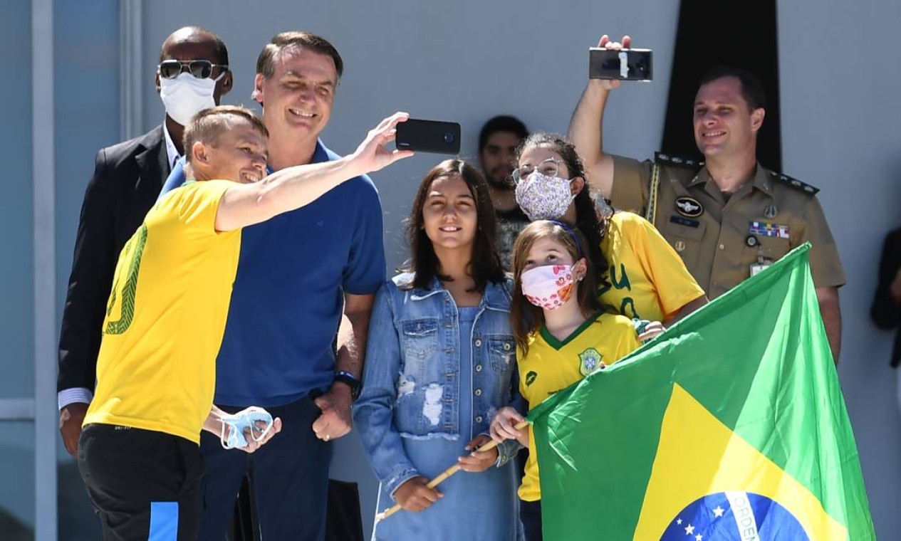 O presidente brasileiro Jair Bolsonaro e sua filha, Laura, posam para uma selfie com apoiadores, do lado de fora do Palácio do Planalto Foto: EVARISTO SA / AFP