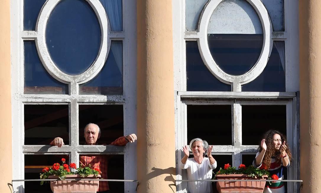 Pessoas aplaudem de sua janela para celebrar o início da fase 2 do confinamento realizado para impedir a propagação da Covid-19 em Roma, na Itália Foto: ALBERTO PIZZOLI / AFP