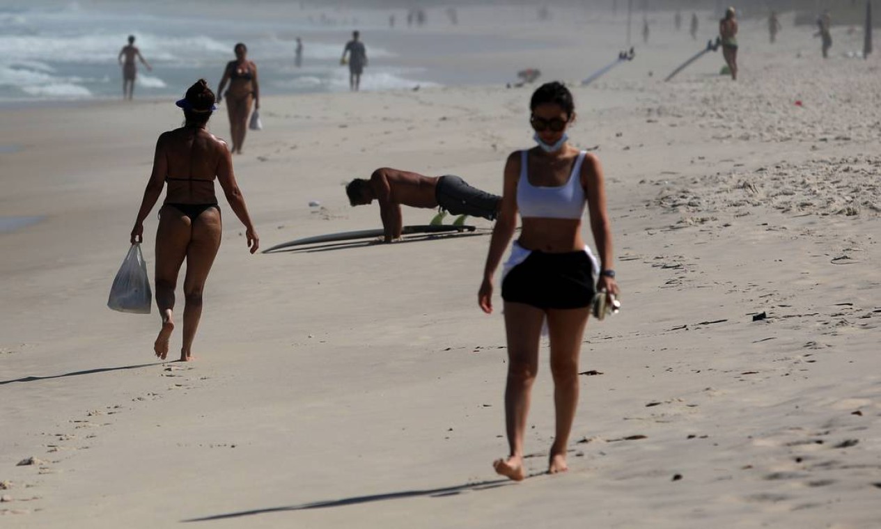 Mulher caminha na areia usando uma máscara de proteção de forma inadequada Foto: FABIO MOTTA / Agência O Globo