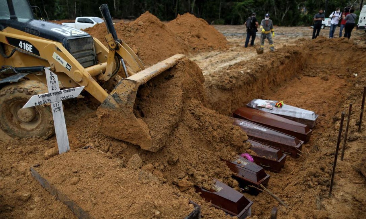 Uma escavadeira cobre os caixões enterrados em uma vala comum no cemitério de Nossa Senhora. Manaus tem 59,3% dos contaminados no estado e mais de 70% das mortes registradas pela doença no Amazonas Foto: MICHAEL DANTAS / AFP