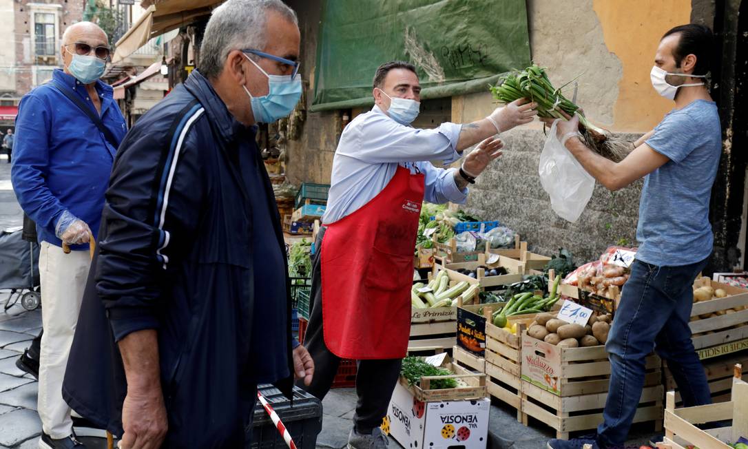 Usando máscaras, moradores de Catânia, no Sul da Itália, compram verduras e legumes; país iniciou desconfinamento na segunda Foto: ANTONIO PARRINELLO / REUTERS