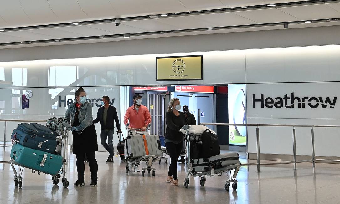 Passageiros usando máscaras de proteção atravessam o saguão de desembarque no Aeroporto de Heathrow, em Londres Foto: JUSTIN TALLIS / AFP
