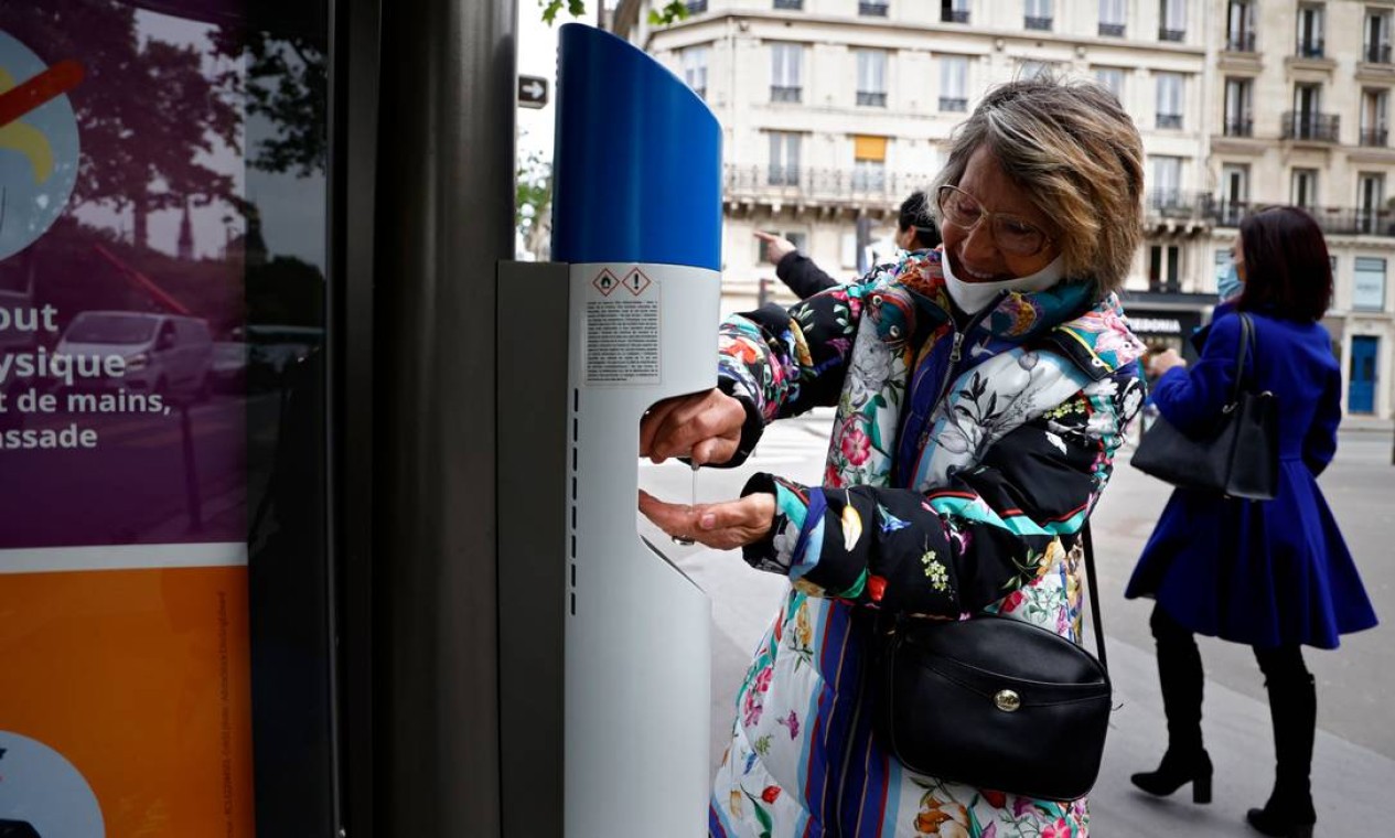 Mulher desinfeta as mãos com álcool em gel em uma parada de ônibus em Paris Foto: THOMAS COEX / AFP
