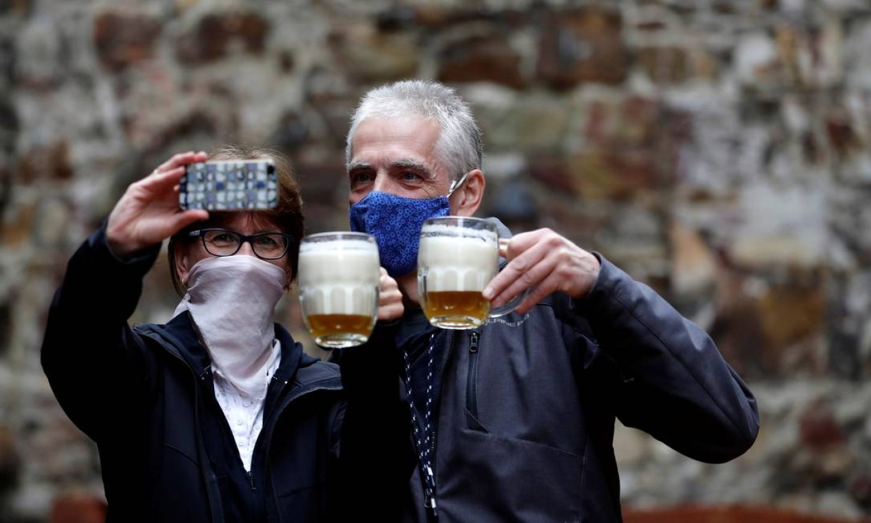 Casal posa para selfie com suas cervejas em área ao ar livre de um pub em Praga, capital da República Tcheca, que autorizou a reabertura de restaurantes com áreas externas em meio ao surto de doença por coronavírus, a partir desta segunda-feira Foto: DAVID W CERNY / REUTERS