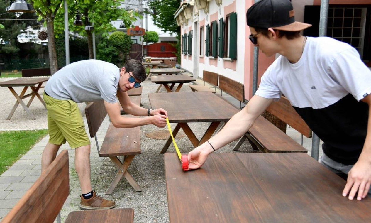 Funcionários do restaurante FuxnGut medem a distância entre as mesas enquanto preparam suas instalações para a reabertura em Salzburgo, na Áustria central Foto: BARBARA GINDL / AFP