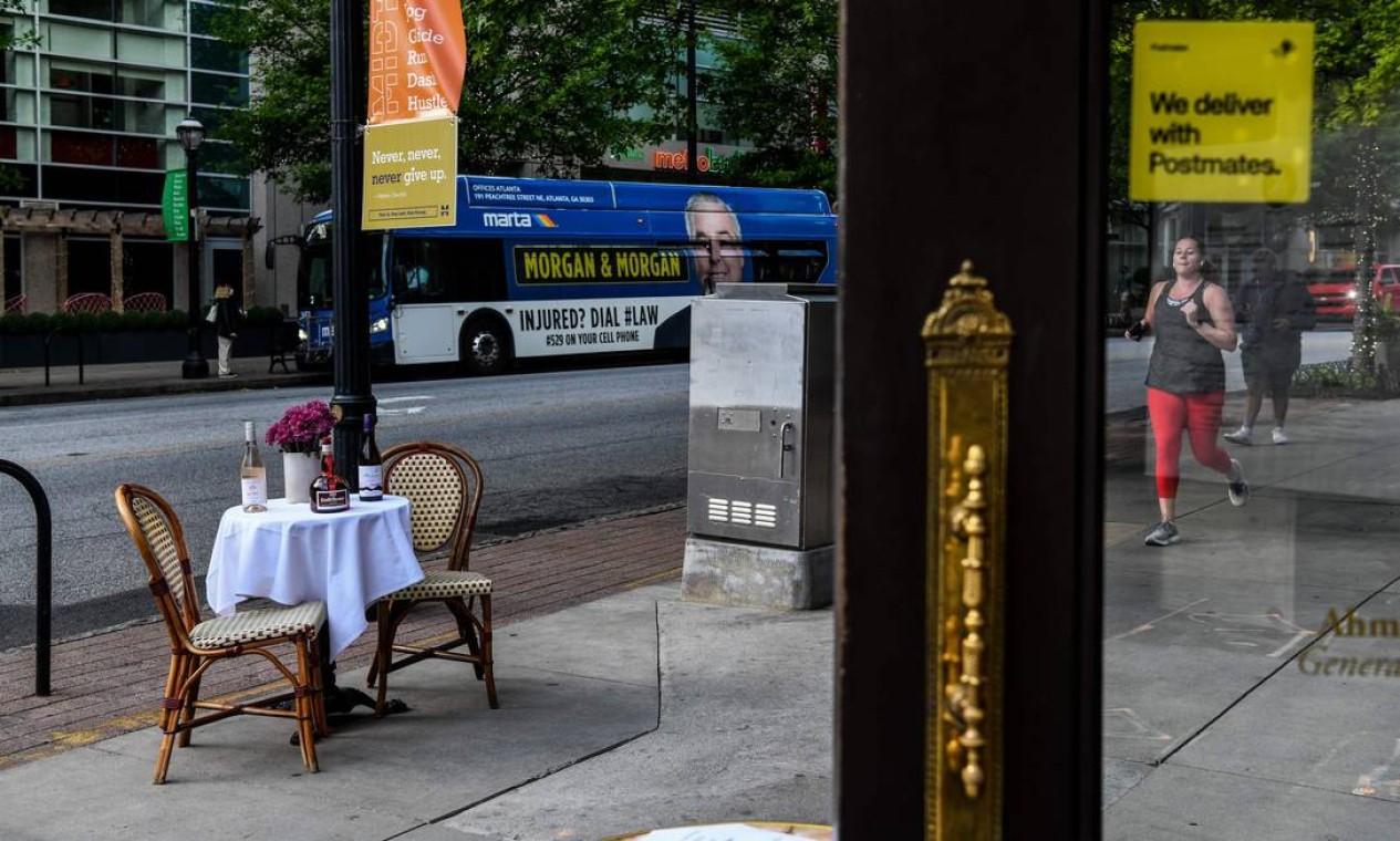 Uma mulher passa por uma mesa de bistrô em frente a um restaurante em Atlanta, Geórgia. Alguns restaurantes da Geórgia reabriram em 27 de abril para um serviço limitado de refeições, à medida que o estado afrouxava o isolamento social Foto: CHANDAN KHANNA / AFP