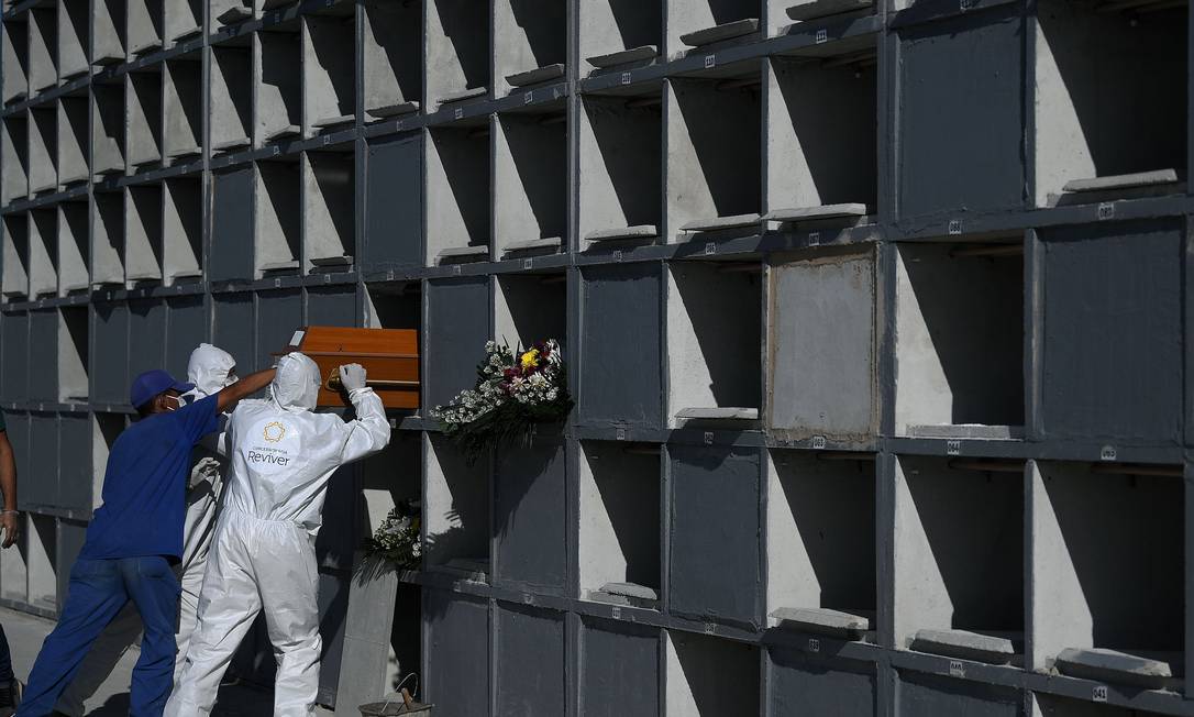 Coveiros posicionam caixão de vítima da Covid-19 em gaveta do cemitério do Caju, na Zona Portuária do Rio, no último dia 9 Foto: CARL DE SOUZA / AFP