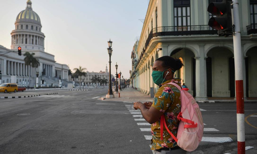 Homem de máscara passa pelo capitólio de Havana Foto: YAMIL LAGE / AFP