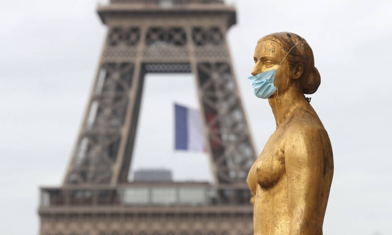 Uma máscara adorna uma estátua na Trocadéro, em frente à Torre Eiffel, em Paris Foto: LUDOVIC MARIN / AFP