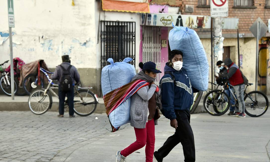 Casal leva mercadorias em rua de El Alto, na Bolívia, no dia 30 de abril Foto: AIZAR RALDES / AFP
