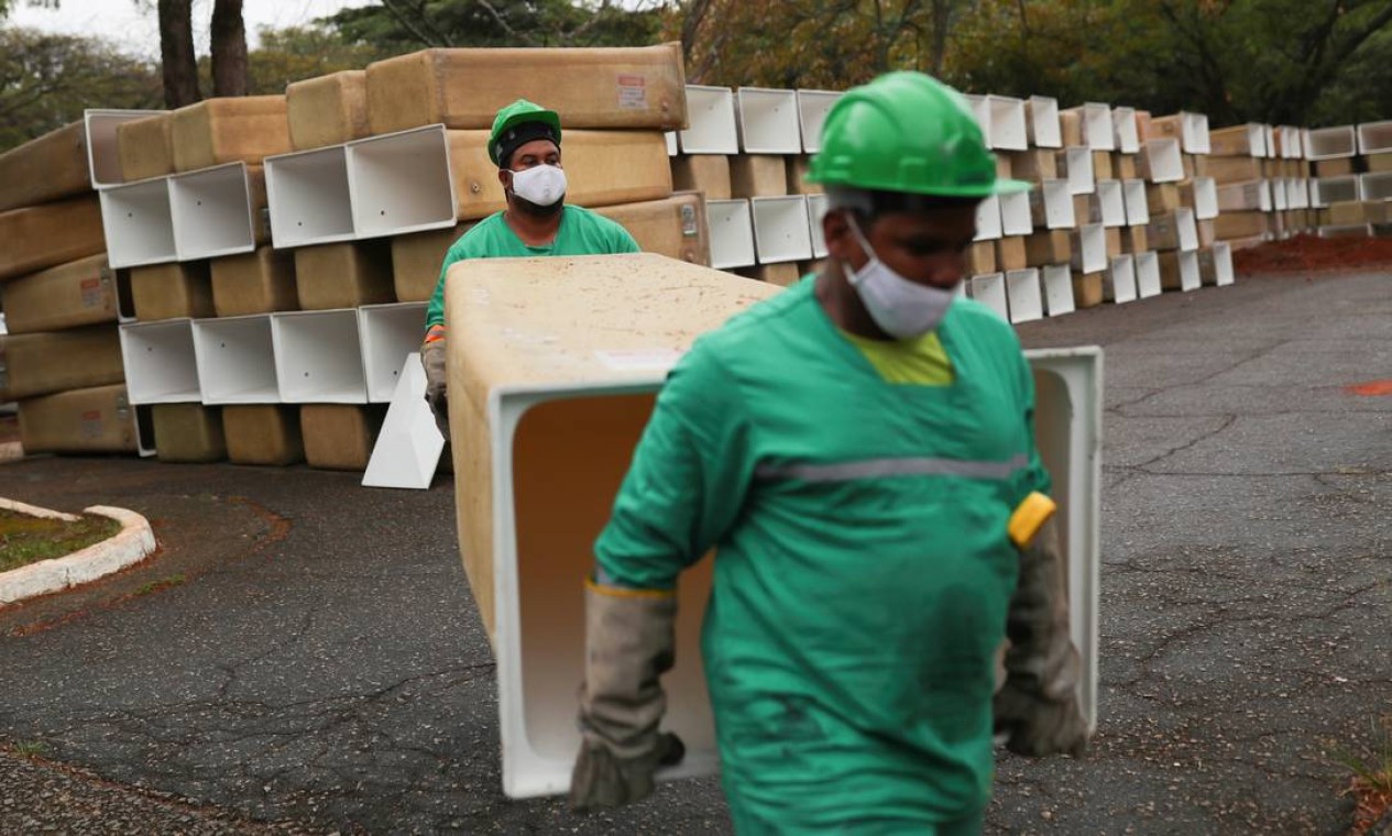 Homens carregam caixas a serem instaladas para os caixões no cemitério municipal de São Pedro, em meio ao surto de coronavírus, em São Paulo Foto: AMANDA PEROBELLI / REUTERS