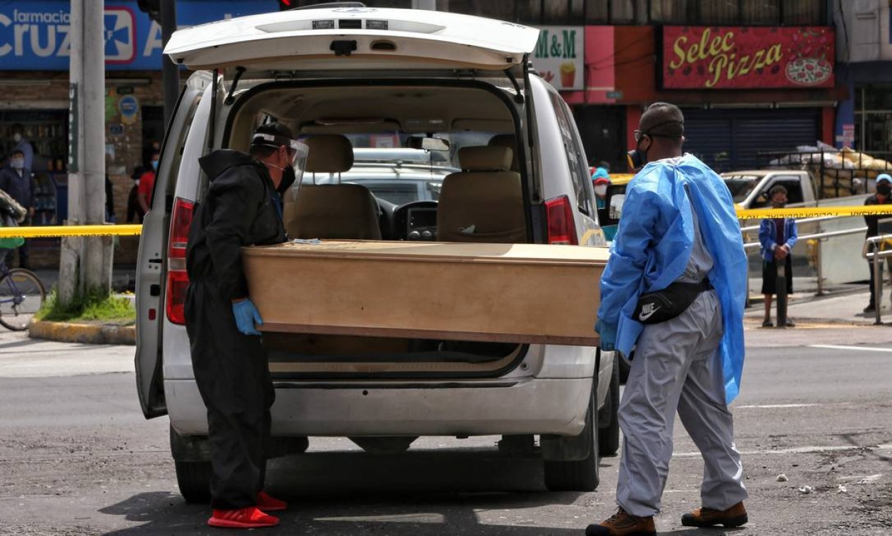 Funcionarios de um serviço funerário removem o corpo de uma mulher que morreu de causas desconhecidas em uma rua de Quito, em meio à pandemia de coronavírus Foto: CRISTINA VEGA RHOR / AFP