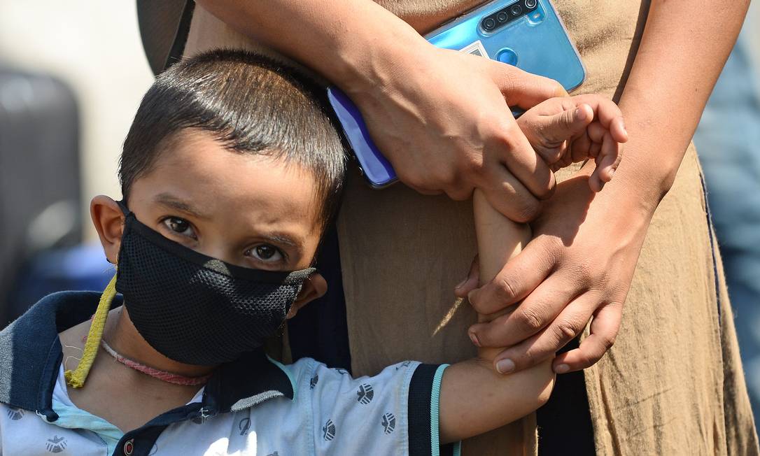 De máscara, criança segura a mão da mãe, na Índia Foto: SAJJAD HUSSAIN / AFP